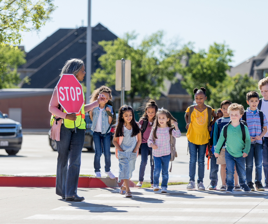 Stock image of a crossing guard helping children through an intersection