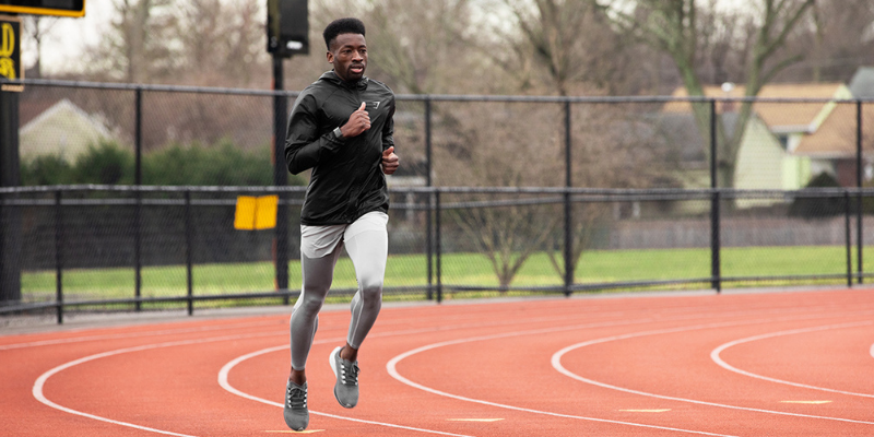 Image of Hellah Sidibe running on a track in white shorts, a black hoodie, and gray sneakers.